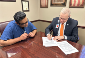 Hillsdale Hospital President and CEO, JJ Hodshire signing paperwork